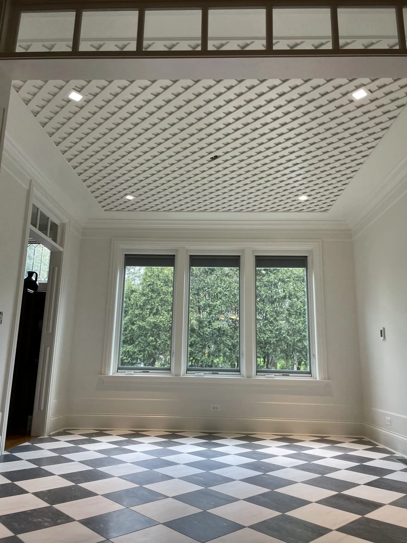 Empty sunroom with a lattice ceiling and three windows