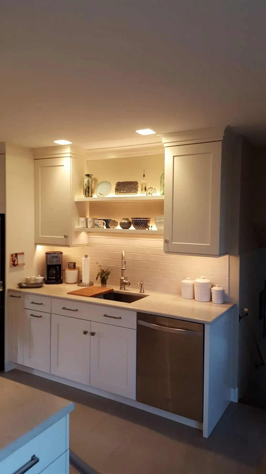 Compact white kitchen with lit open shelves over the sink