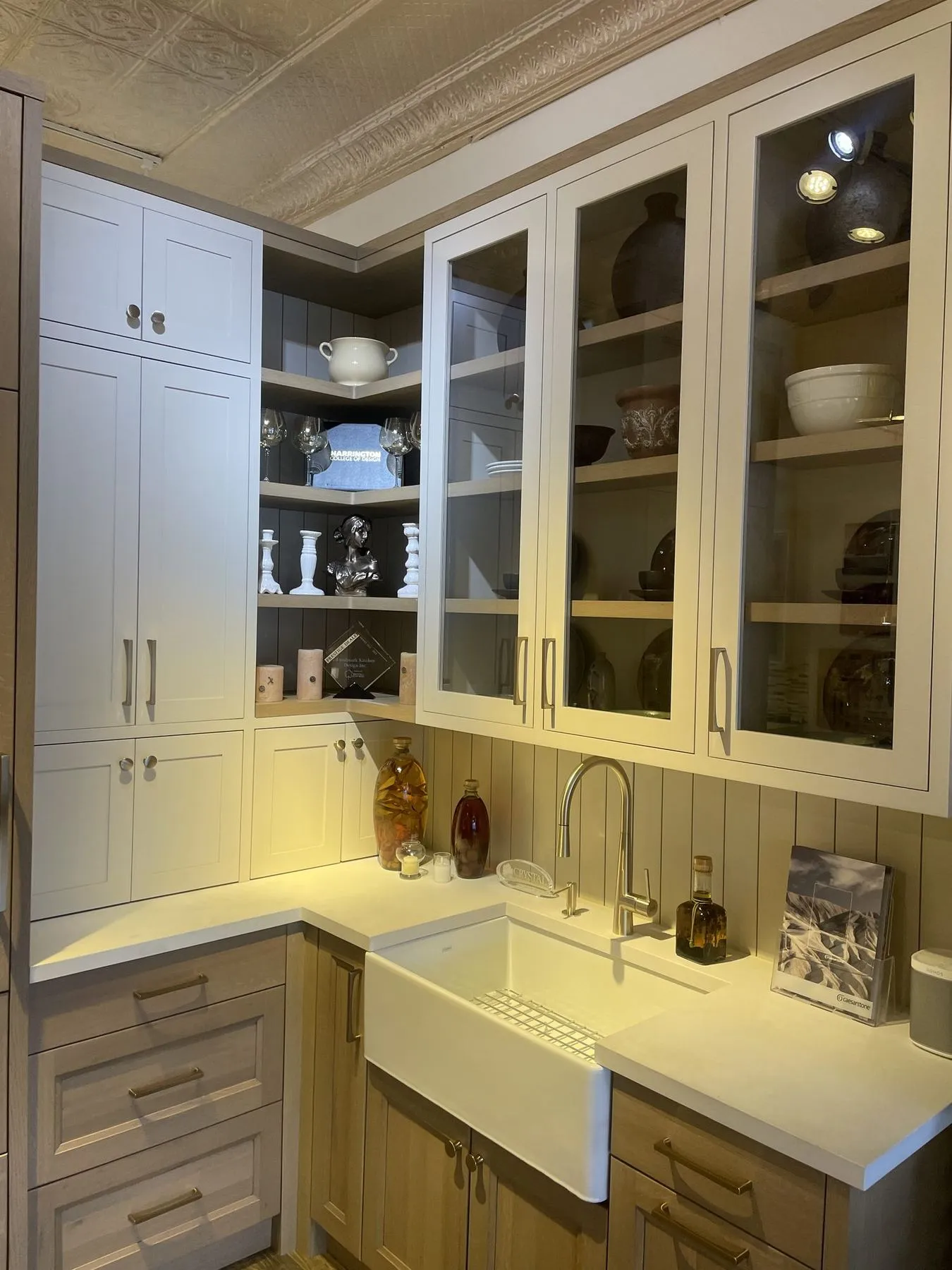 Corner of a kitchen with glass cabinets over a farmhouse sink