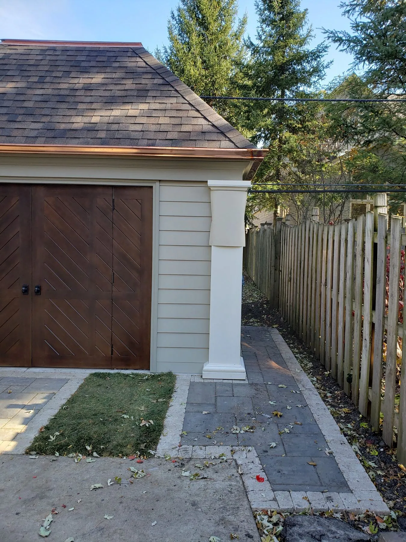 Detached garage with wood doors and a paver walk