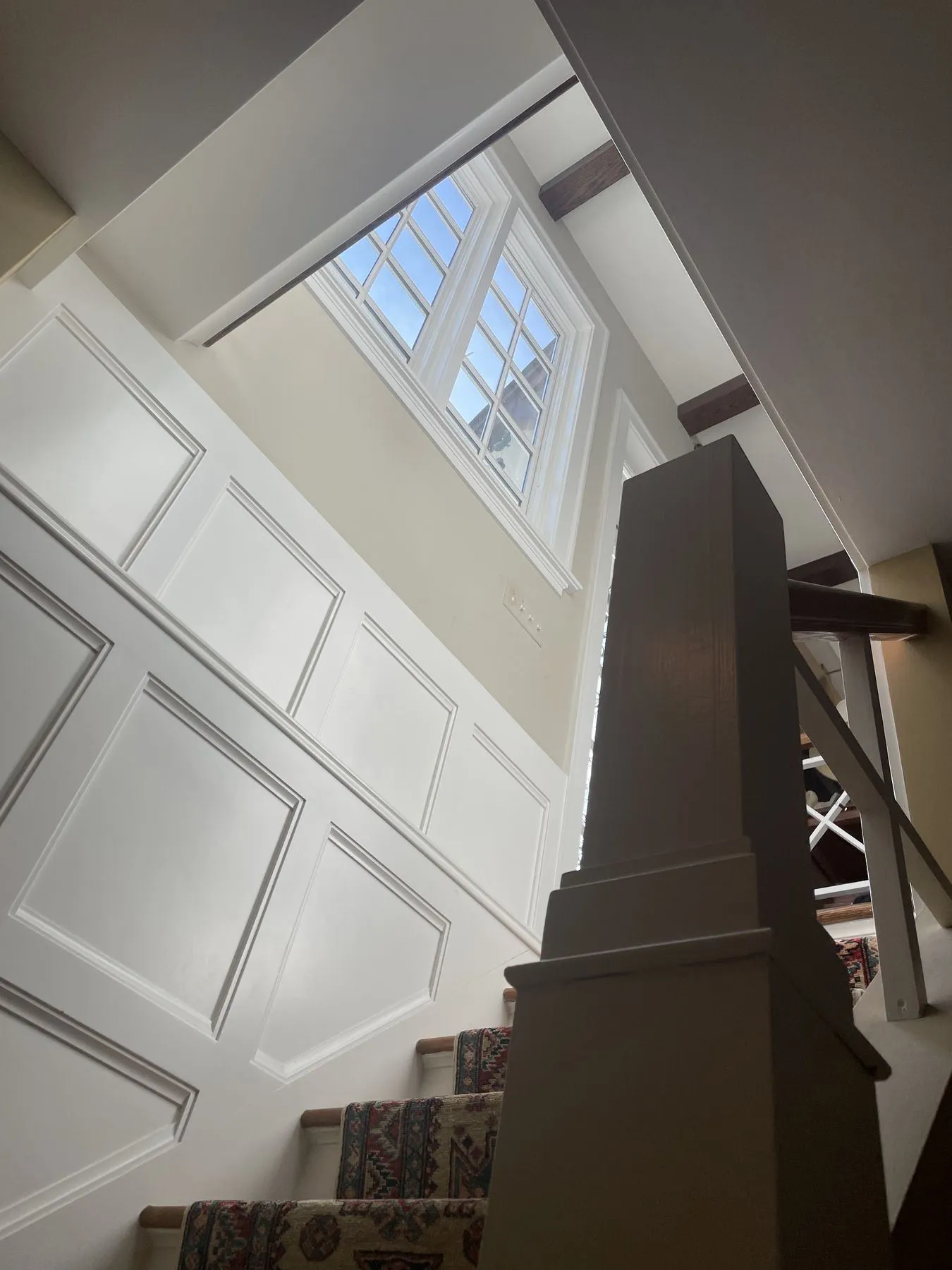 Paneled walls and a tall newel post at the top of the stairs
