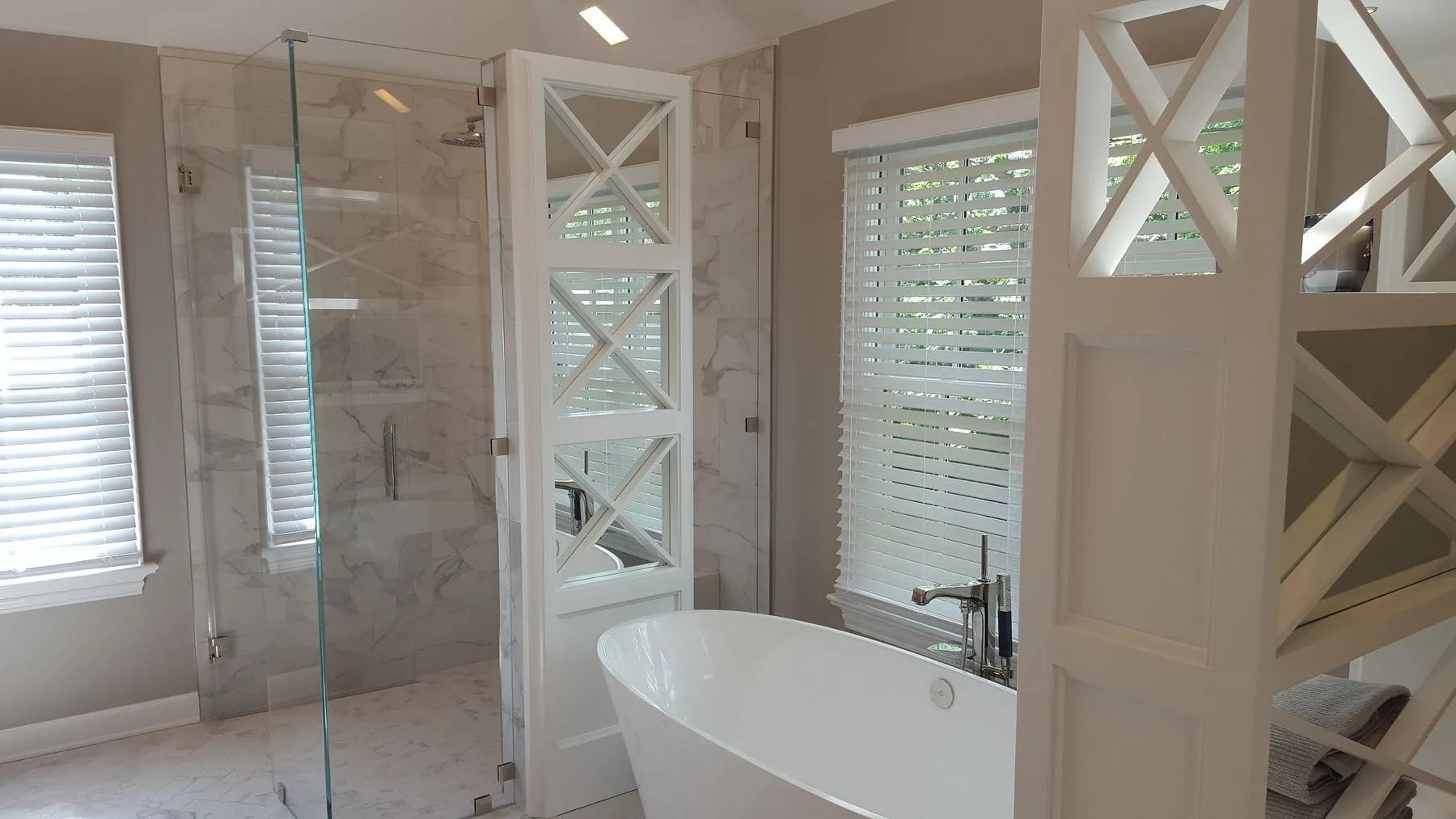 Glass shower and freestanding tub beside the X-pattern storage tower