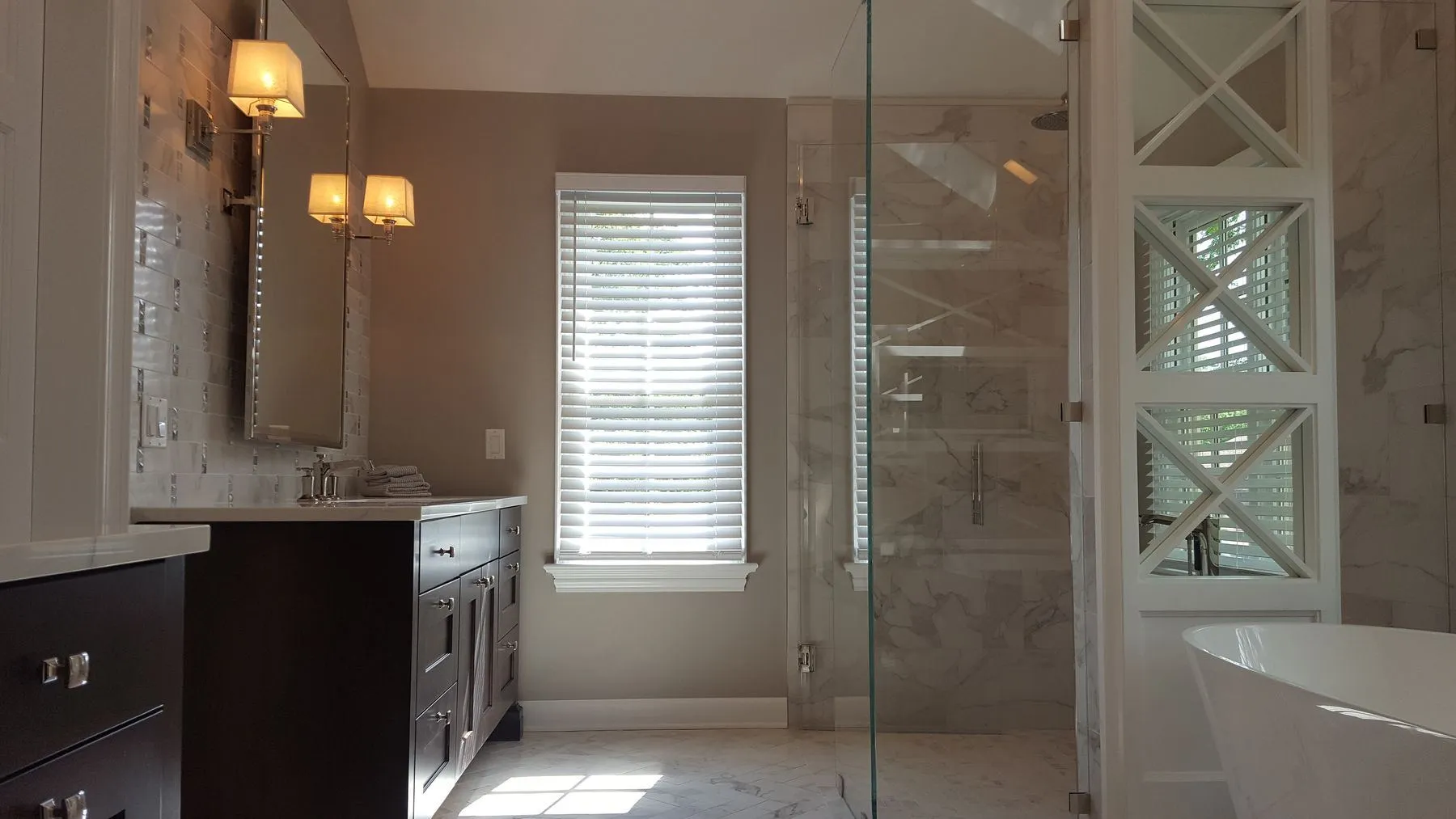 Dark vanity, sconces, and glass shower