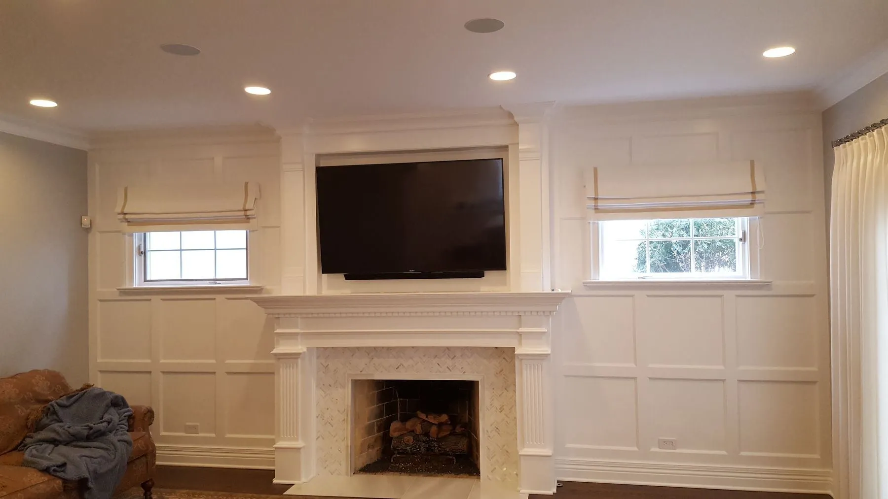 Paneled wall with a fireplace, TV, and two small windows