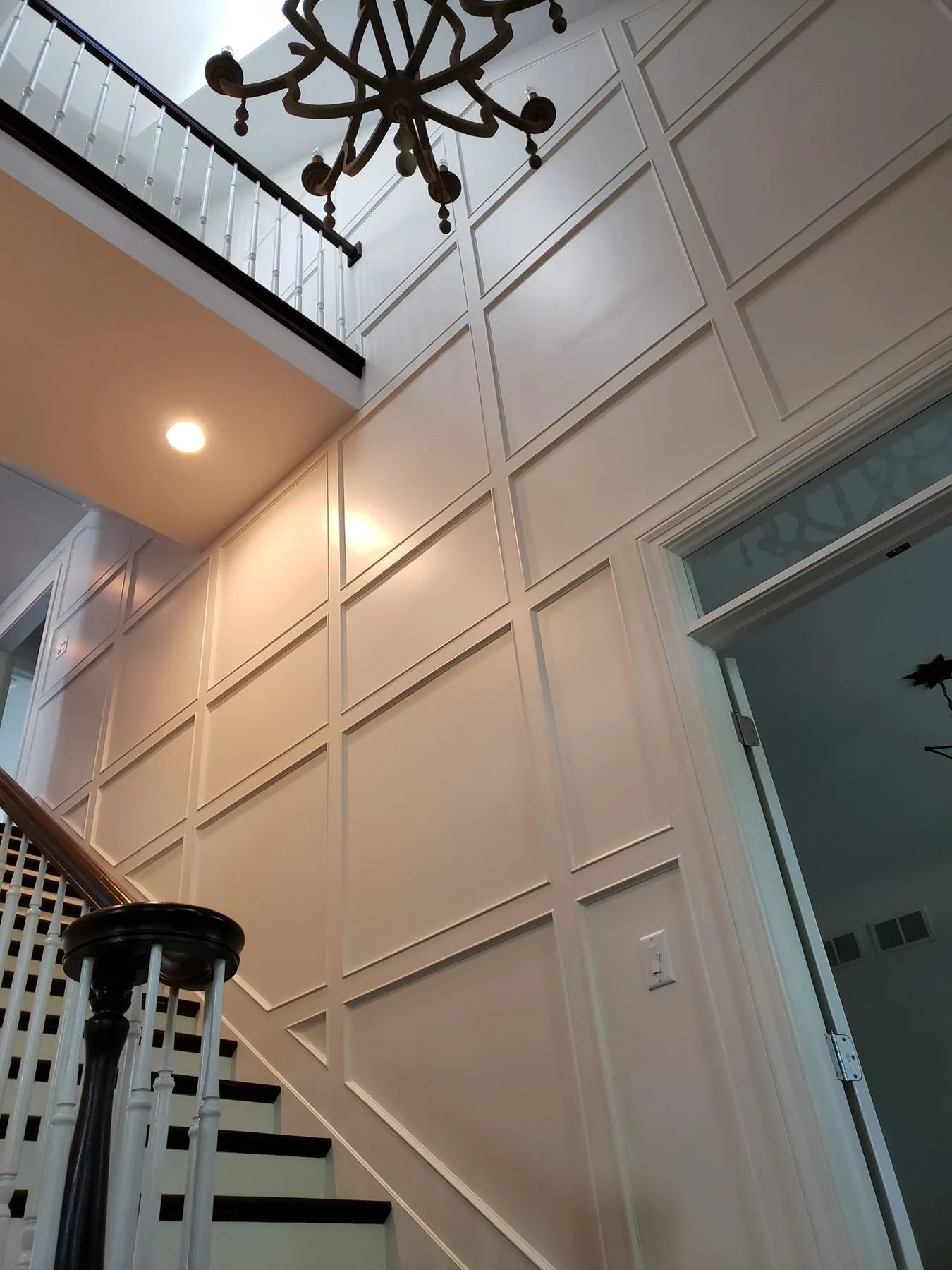 Two-story paneled wall under a chandelier