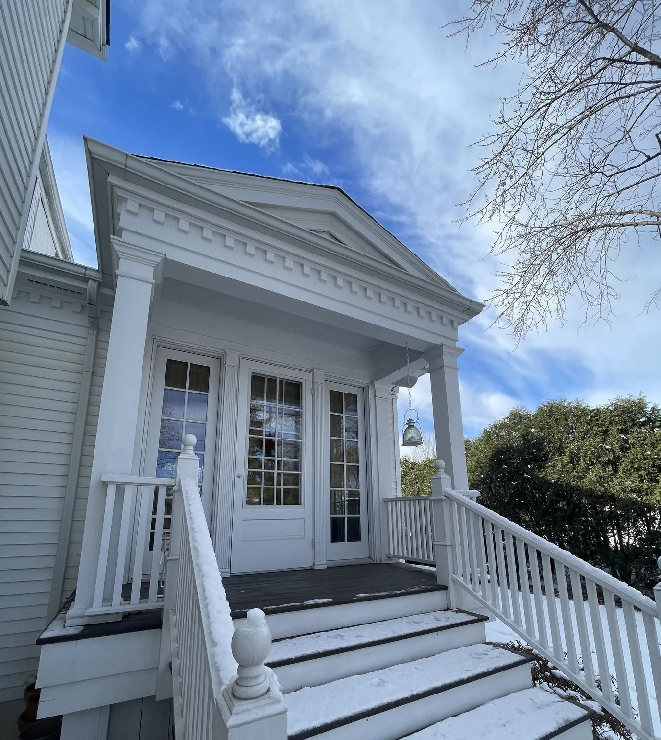 Close view of the entry porch, railings, and French doors