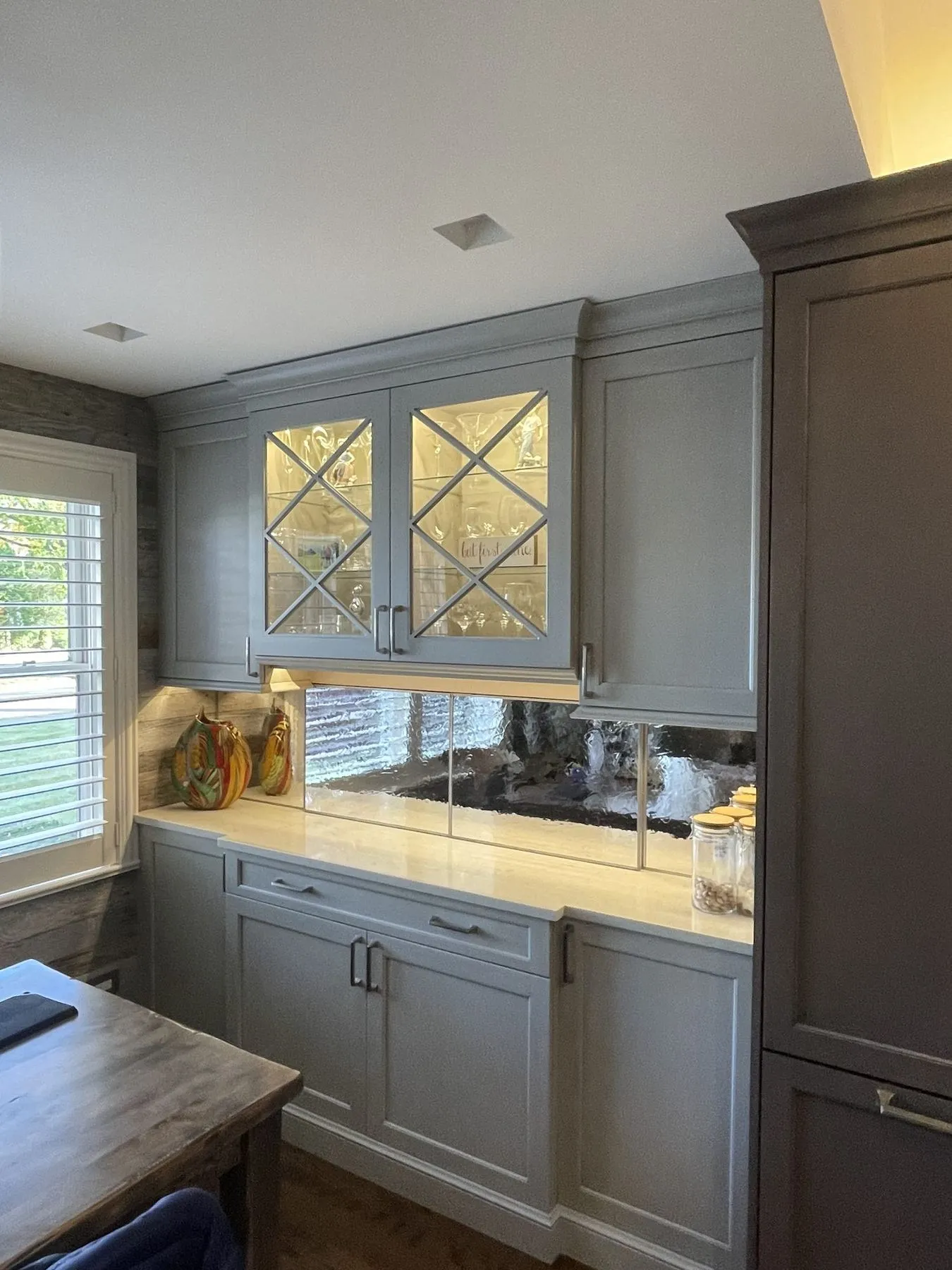 Gray cabinets with X-pattern glass doors over a counter