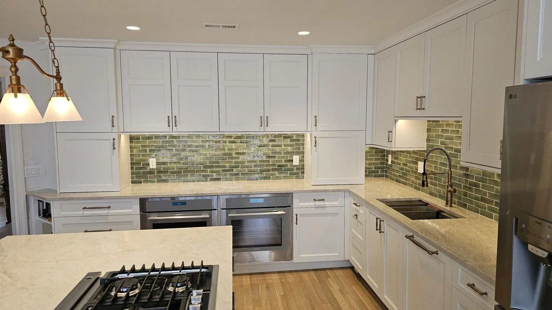 Cooktop island in the foreground with the sink run and green tile behind